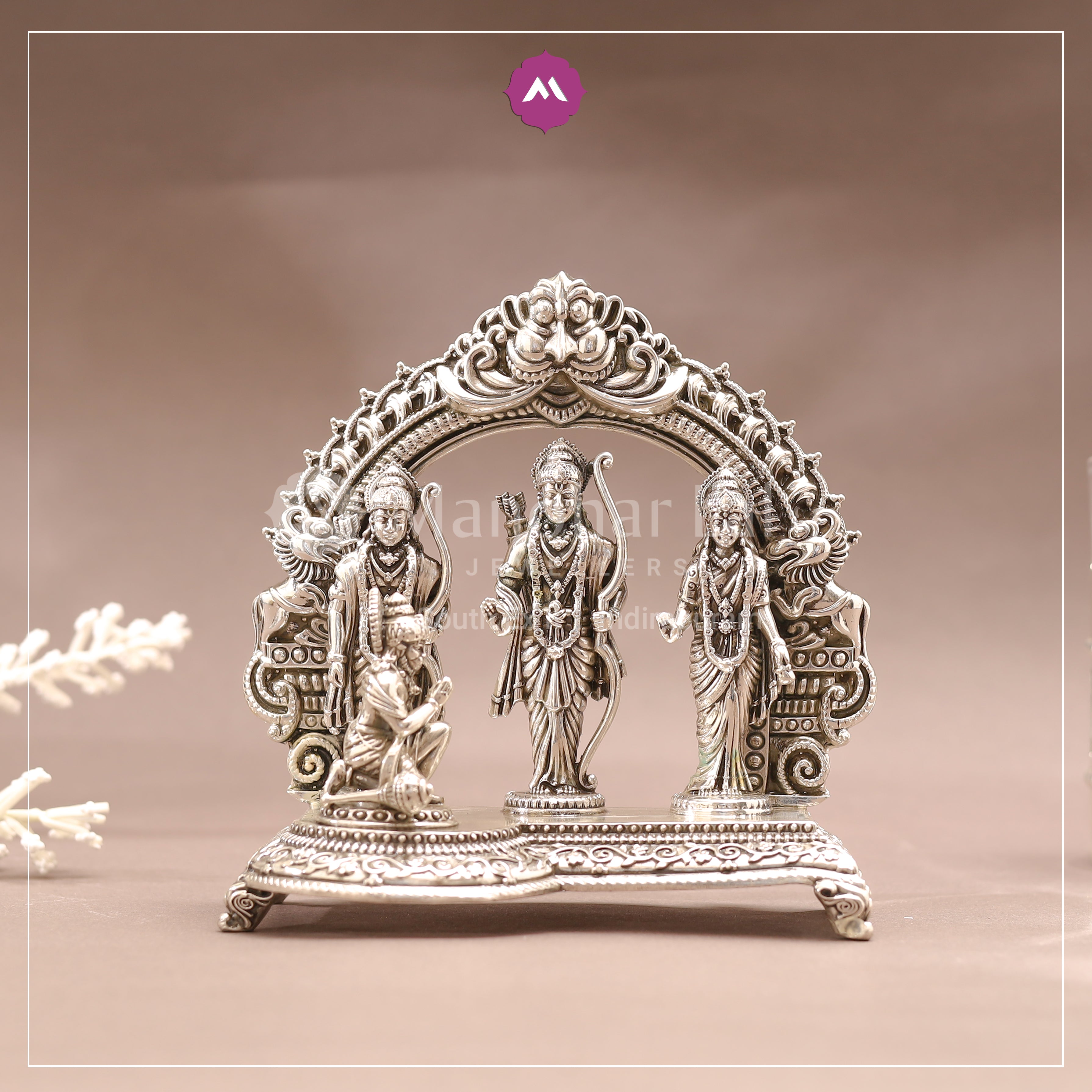 Decorative silver statue of three figures on a brown background
